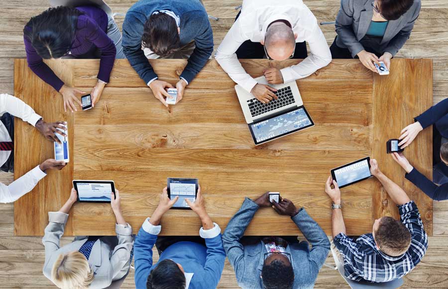 people sitting at table with mobile devices
